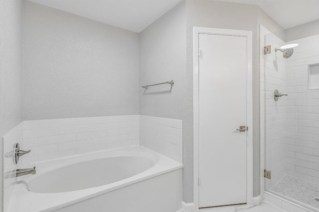 full bath with a garden tub, marble finish floor, a stall shower, a textured wall, and baseboards