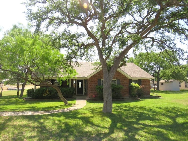 single story home featuring roof with shingles, brick siding, and a front lawn