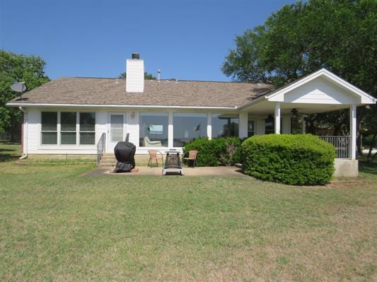 back of property with a chimney and a lawn