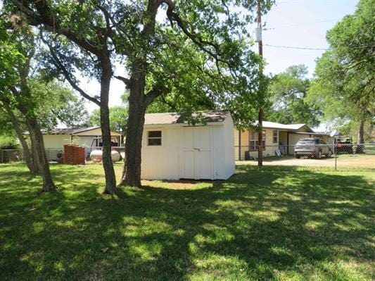 view of yard featuring a shed, fence, and an outdoor structure