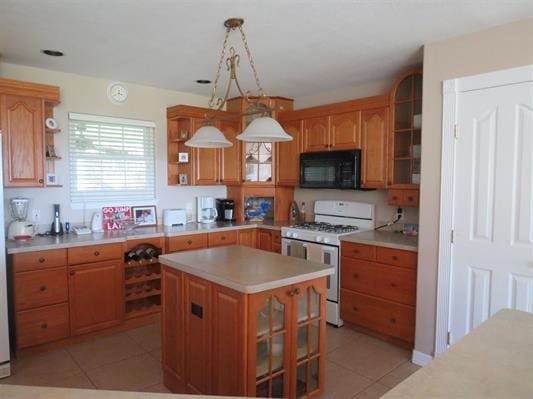 kitchen featuring range with gas stovetop, black microwave, light tile patterned floors, light countertops, and open shelves