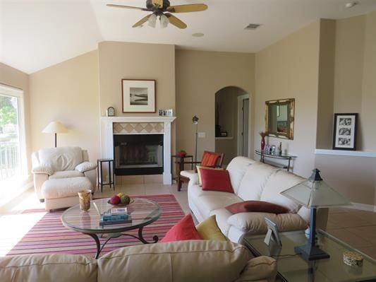 living area featuring arched walkways, ceiling fan, visible vents, and light tile patterned floors