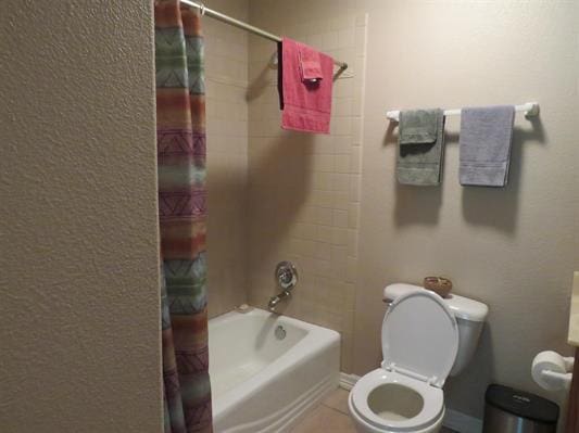 bathroom featuring tile patterned floors, toilet, and shower / bathtub combination with curtain