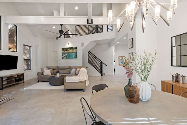 dining area with baseboards, stairway, ceiling fan with notable chandelier, high vaulted ceiling, and finished concrete floors
