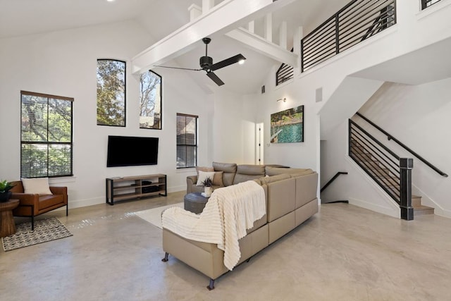 living area featuring baseboards, a ceiling fan, stairs, high vaulted ceiling, and finished concrete floors