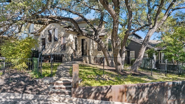 view of front of house with a fenced front yard, stucco siding, and a gate