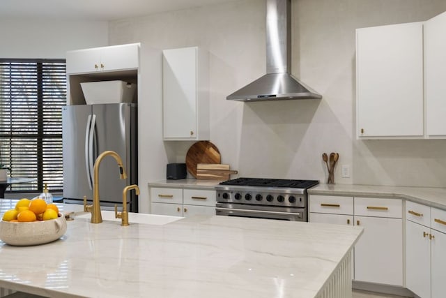 kitchen with stainless steel appliances, wall chimney exhaust hood, white cabinetry, and a healthy amount of sunlight