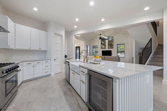 1018 Harwood Pl, Austin, TX 78704 - kitchen featuring stainless steel appliances, wine cooler, a ceiling fan, finished concrete floors, and an island with sink