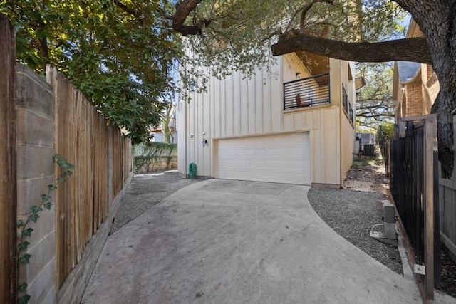 exterior space with board and batten siding, driveway, fence, and a garage