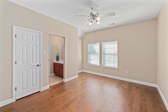 unfurnished bedroom featuring visible vents, baseboards, ensuite bath, and light wood-style floors