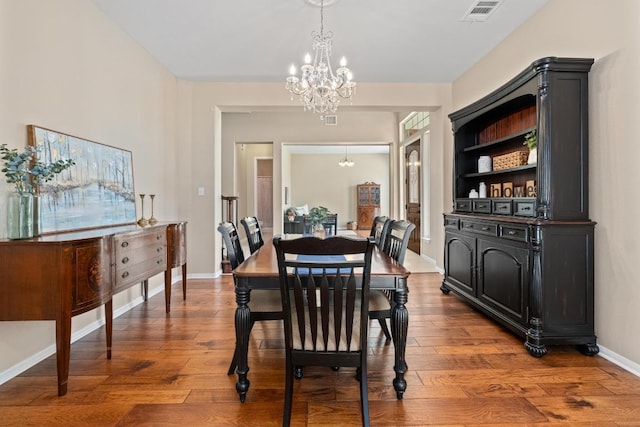 dining space featuring a chandelier, visible vents, baseboards, and wood finished floors