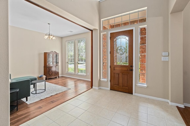 entryway featuring an inviting chandelier, baseboards, and light tile patterned floors