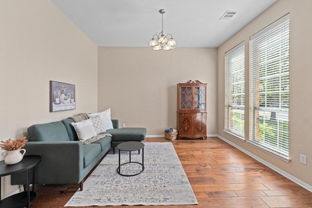 living room with a chandelier, visible vents, wood finished floors, and a healthy amount of sunlight