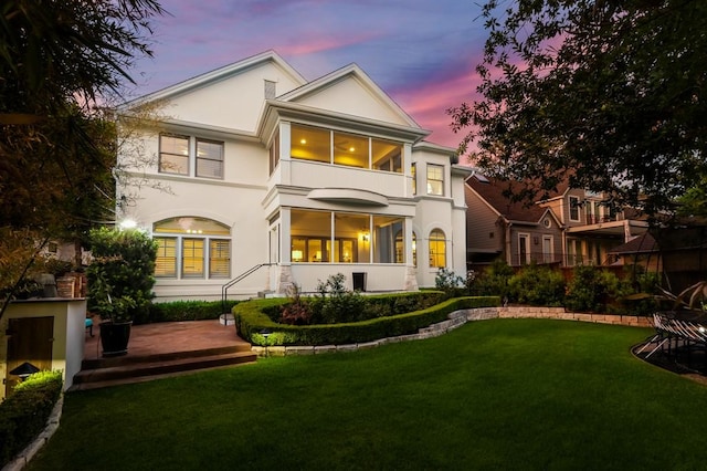 rear view of house featuring stucco siding and a lawn