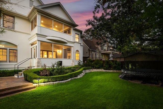 rear view of house featuring a yard and stucco siding