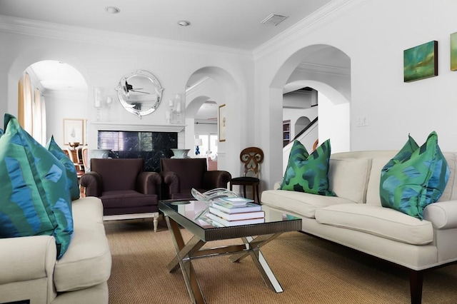 carpeted living room with arched walkways, visible vents, and crown molding