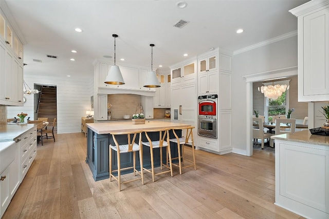 2601 Buckminister Ct, Austin, TX 78746 - kitchen featuring white cabinets, a chandelier, light countertops, ornamental molding, and recessed lighting