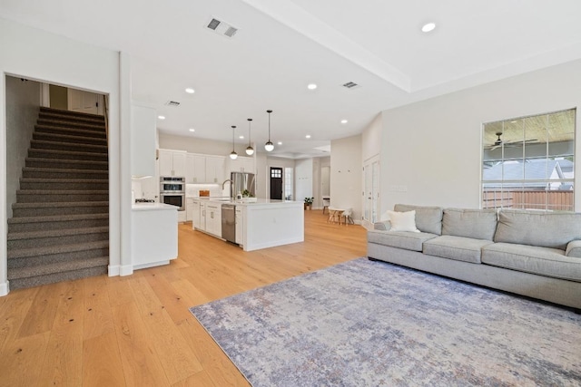 113 Oak Plaza Dr, Georgetown, TX 78628 - living area with stairway, light wood finished floors, visible vents, and a wealth of natural light