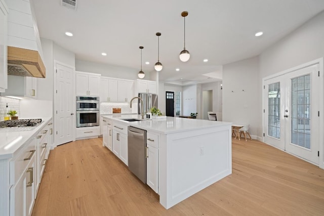 113 Oak Plaza Dr, Georgetown, TX 78628 - kitchen featuring light wood-style flooring, appliances with stainless steel finishes, decorative backsplash, and a sink
