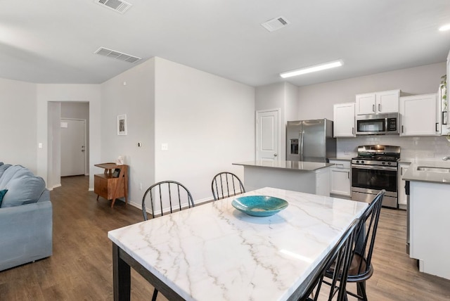 10805 Dimitrios Dr, Austin, TX 78747 - kitchen with stainless steel appliances, a kitchen island, dark wood finished floors, and decorative backsplash
