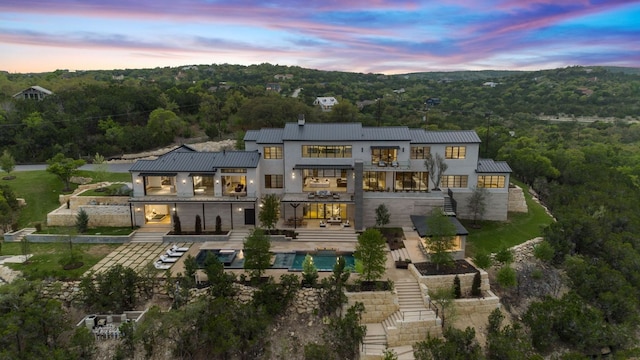 4816 Pecan Chase, Austin, TX 78738 - back of property at dusk featuring stairway, a balcony, a forest view, and a patio