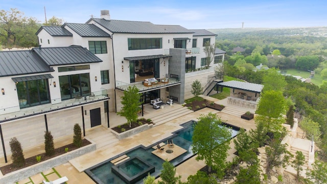 4816 Pecan Chase, Austin, TX 78738 - back of property featuring a standing seam roof, stucco siding, metal roof, a pool with connected hot tub, and a chimney