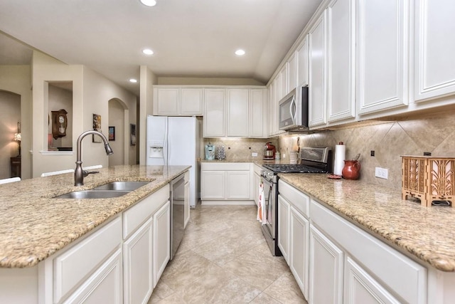 1904 Cactus Mound Dr, Leander, TX 78641 - kitchen with appliances with stainless steel finishes, arched walkways, white cabinets, backsplash, and light stone countertops