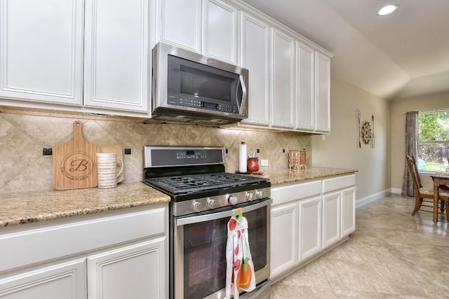 1904 Cactus Mound Dr, Leander, TX 78641 - kitchen featuring appliances with stainless steel finishes, white cabinetry, backsplash, vaulted ceiling, and light stone countertops