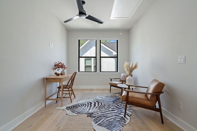 sitting room featuring attic access, light wood-style floors, and baseboards