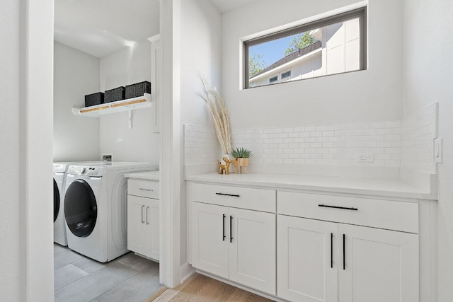 clothes washing area featuring independent washer and dryer, cabinet space, and light wood finished floors