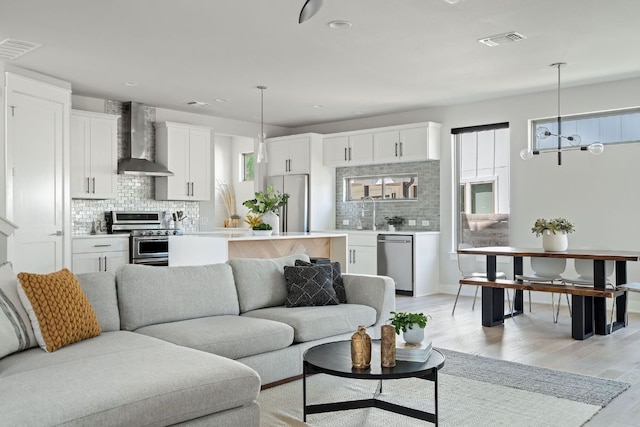 living area featuring light wood finished floors, baseboards, a chandelier, and recessed lighting