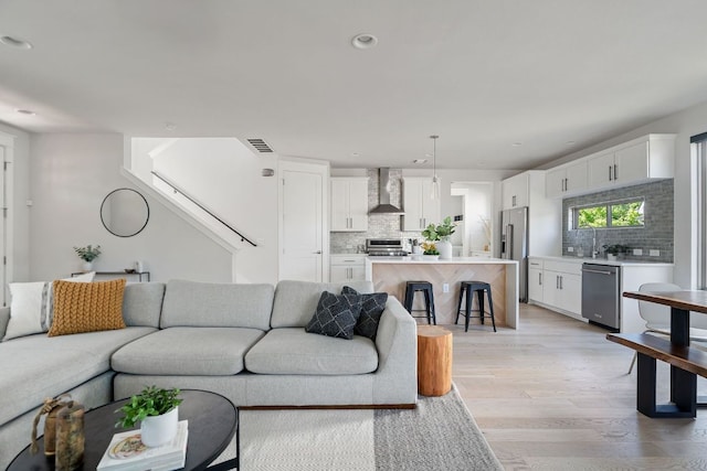 living area featuring light wood finished floors, stairs, and recessed lighting