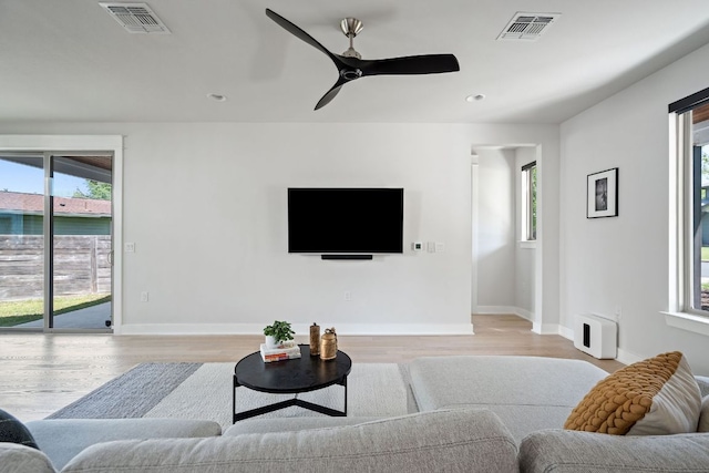 living room featuring healthy amount of natural light, light wood finished floors, ceiling fan, baseboards, and recessed lighting