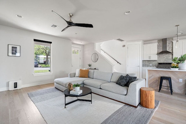 living room with stairway, light wood-type flooring, a ceiling fan, recessed lighting, and baseboards