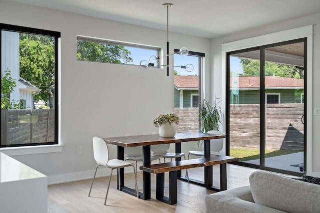 dining area featuring healthy amount of natural light, a chandelier, light wood finished floors, and baseboards