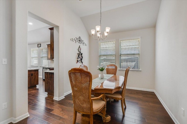 dining area with dark wood-type flooring, a chandelier, baseboards, and vaulted ceiling