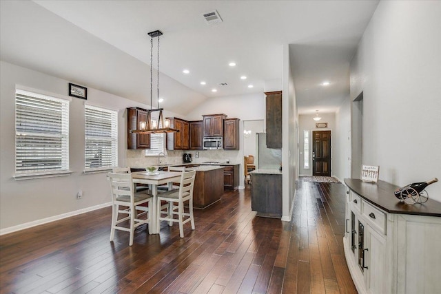 dining space with dark wood finished floors, visible vents, baseboards, and lofted ceiling