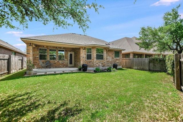 rear view of house featuring brick siding, a fenced backyard, a patio, and a lawn