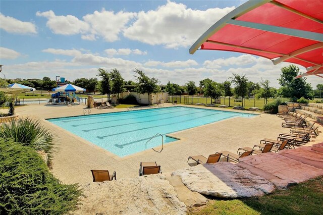 community pool with a patio and fence