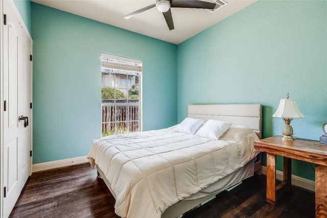 bedroom with baseboards, a ceiling fan, visible vents, and wood finished floors