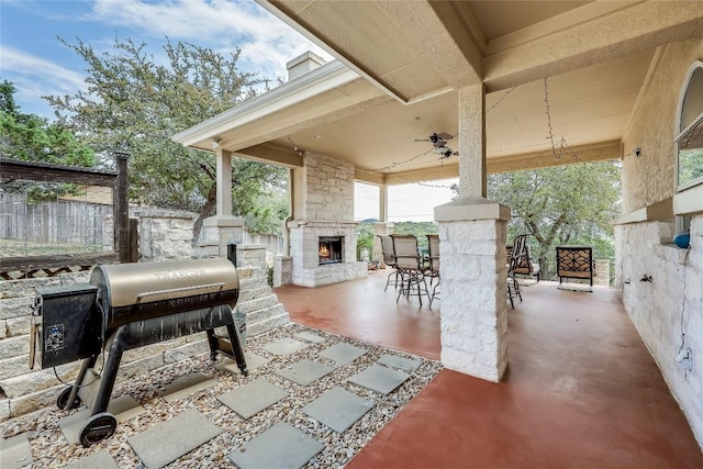 view of patio with an outdoor stone fireplace and fence