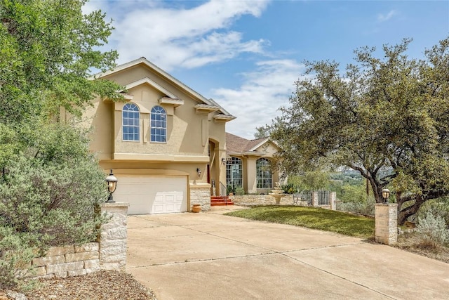 view of front of house featuring driveway, stucco siding, stone siding, and an attached garage
