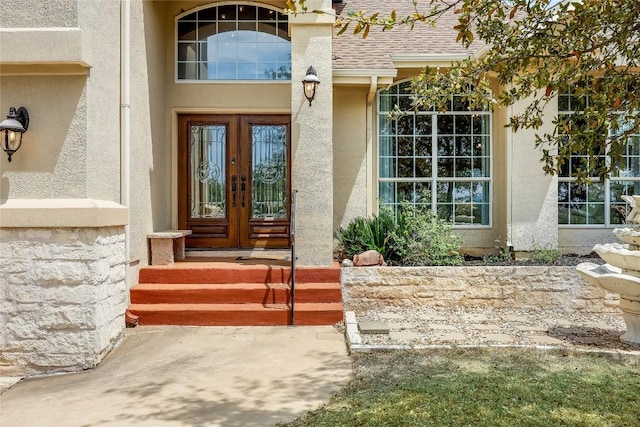 view of exterior entry with stucco siding, roof with shingles, and french doors