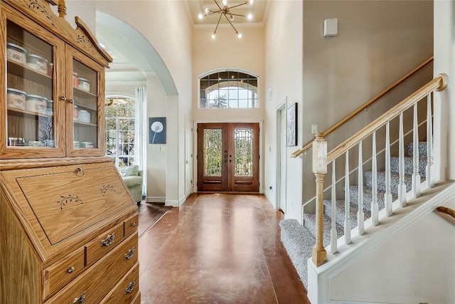 entrance foyer with stairs, ornamental molding, arched walkways, a high ceiling, and baseboards