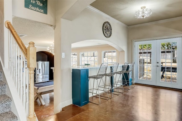 foyer with plenty of natural light, stairway, french doors, and ornamental molding