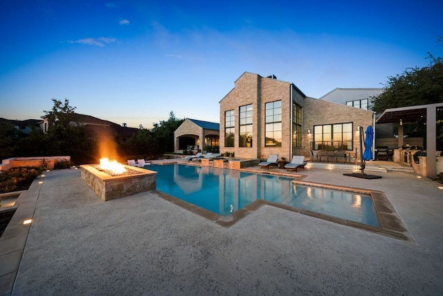pool at dusk featuring a patio, a fire pit, and an outdoor pool