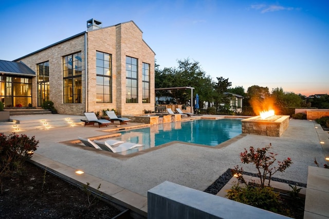 pool at dusk with a fire pit, an outdoor pool, and a patio area