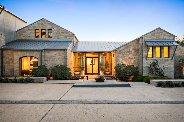view of front of property with stone siding, a standing seam roof, and metal roof