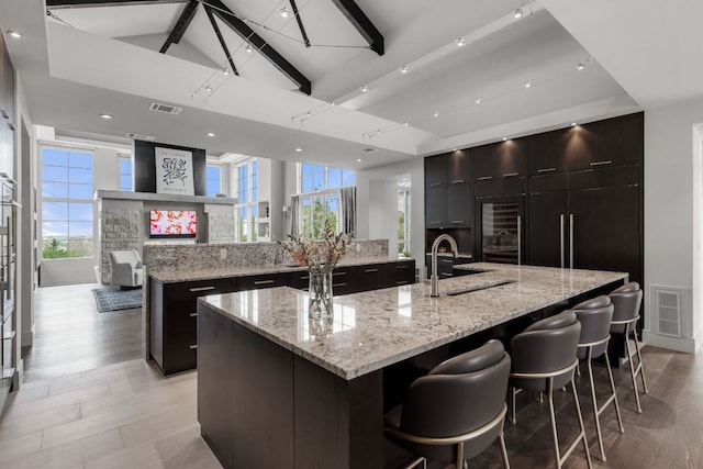 kitchen featuring visible vents, a spacious island, a kitchen breakfast bar, and a sink