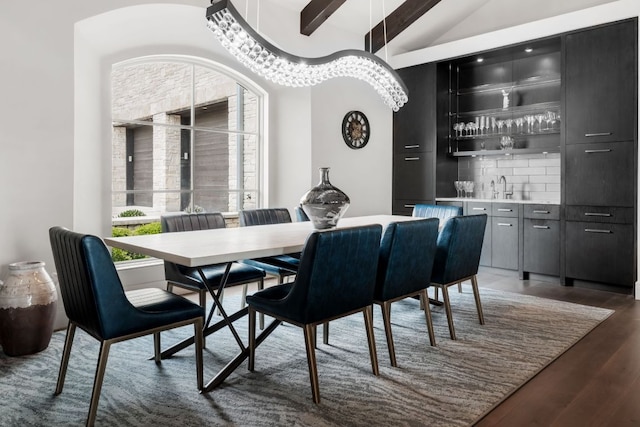 dining room featuring wood finished floors, lofted ceiling with beams, and indoor wet bar